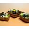 Front of three handmade acacia bowls displaying a green and natural colored blend of botanicals. Bowl shapes are square, leaf, and flare.